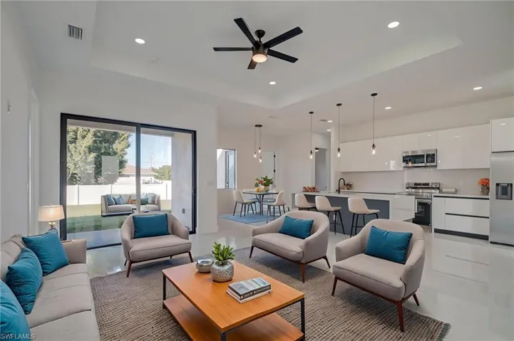 Living area with a tray ceiling, a ceiling fan, and recessed lighting