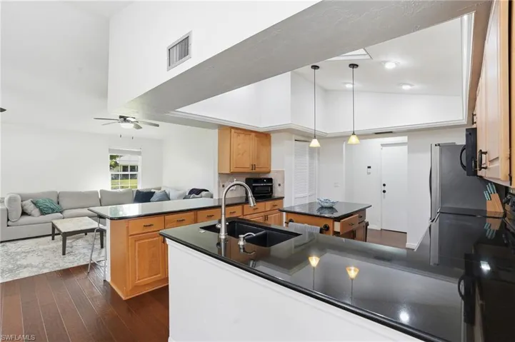 Kitchen featuring a peninsula, decorative light fixtures, dark wood finished floors, open floor plan, and high vaulted ceiling