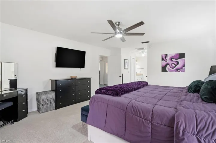 Bedroom with light colored carpet and a ceiling fan