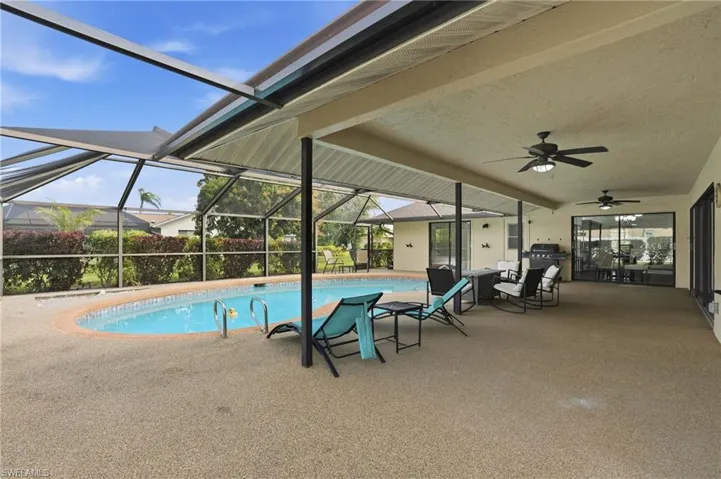 Outdoor pool featuring a patio, a sunroom, glass enclosure, and grilling area