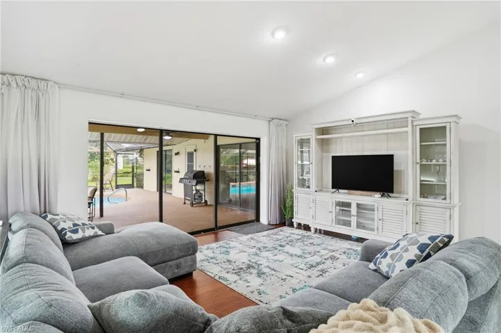 Living room with wood finished floors, vaulted ceiling, and recessed lighting