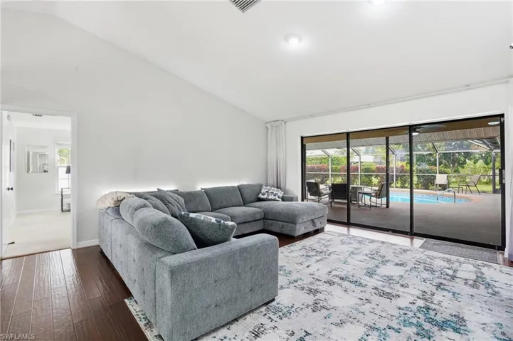 Living area with a sunroom, hardwood / wood-style floors, and high vaulted ceiling