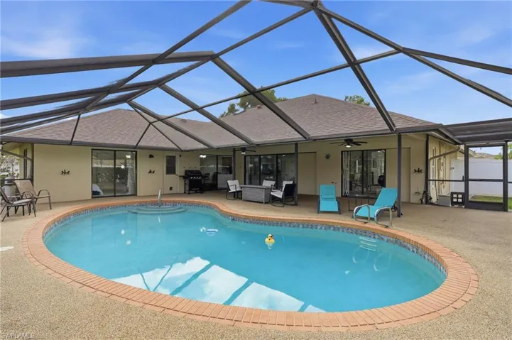 Outdoor pool with glass enclosure, a sunroom, area for grilling, and a patio
