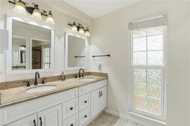 Full bath with double vanity, an enclosed shower, and light tile patterned flooring