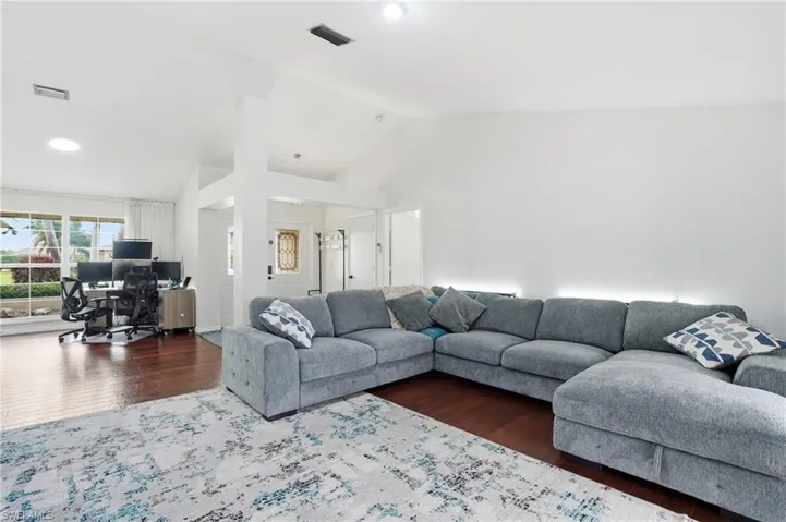 Living area with an office area, dark wood-style flooring, and high vaulted ceiling