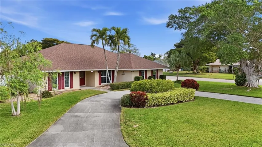 Ranch-style home featuring a front yard, a shingled roof, stucco siding, and asphalt driveway