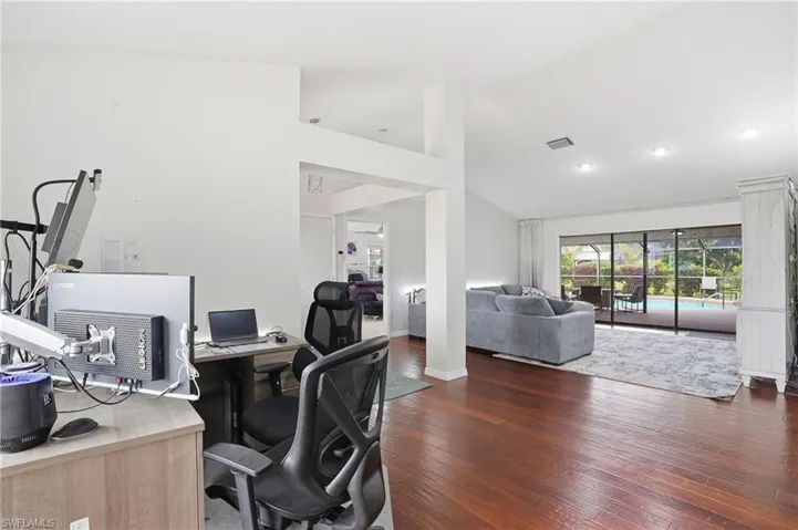Office area with dark wood-style floors and high vaulted ceiling
