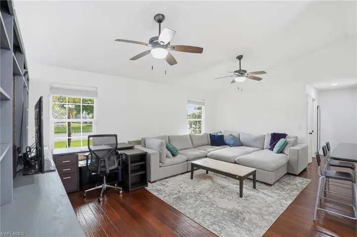 Living room featuring dark wood finished floors, vaulted ceiling, healthy amount of natural light, and ceiling fan