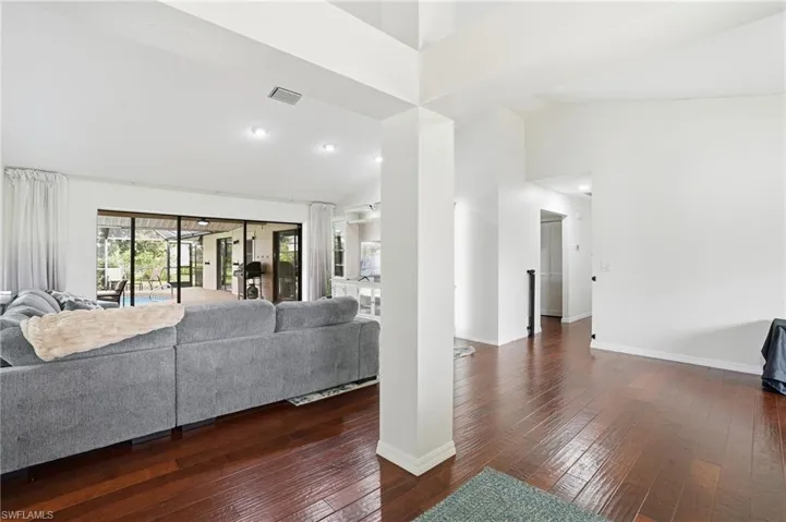 Living area with dark wood-style floors, high vaulted ceiling, and recessed lighting