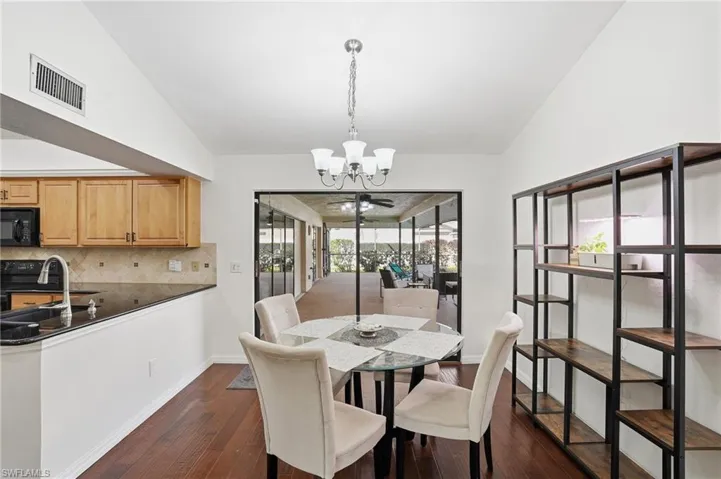 Dining area with lofted ceiling, a chandelier, and dark wood finished floors