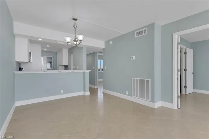 Unfurnished room with a chandelier and baseboards
