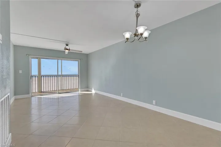 Unfurnished room with a chandelier, light tile patterned flooring, and a ceiling fan