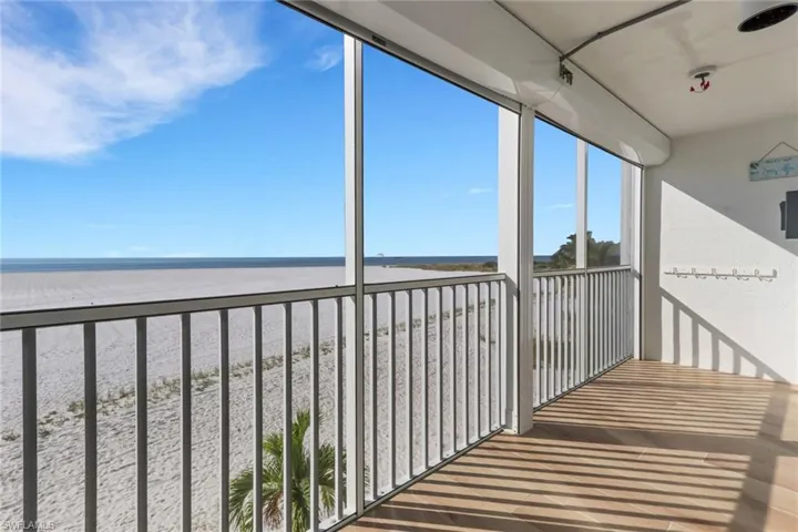 Balcony featuring a sunroom and view of water and beach