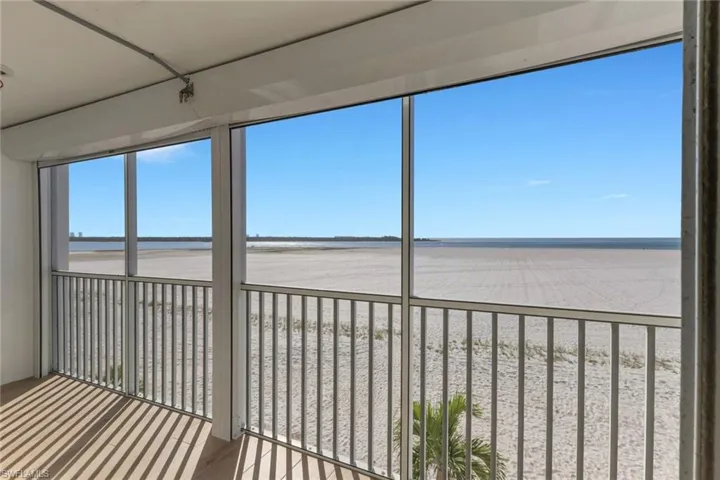 Unfurnished sunroom featuring view of water and beach