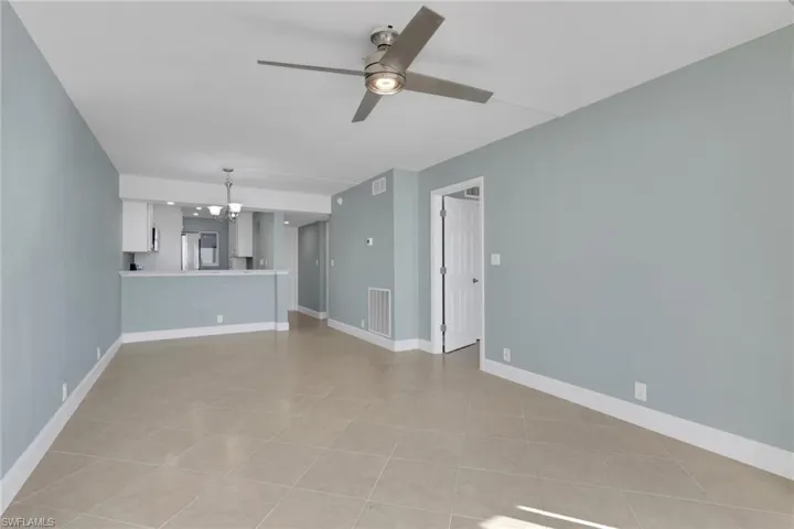 Unfurnished living room with a chandelier and ceiling fan
