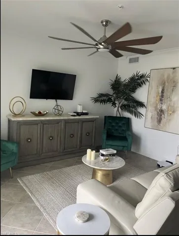 Living area with crown molding, ceiling fan, and light tile patterned flooring
