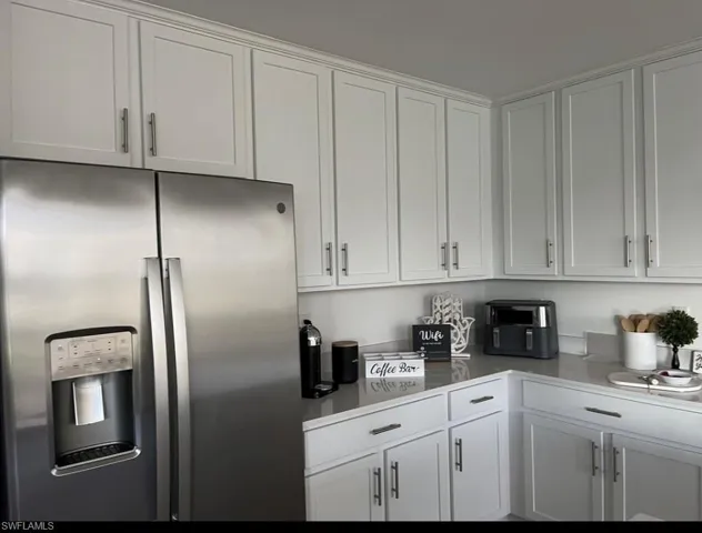 Kitchen featuring stainless steel fridge and white cabinetry