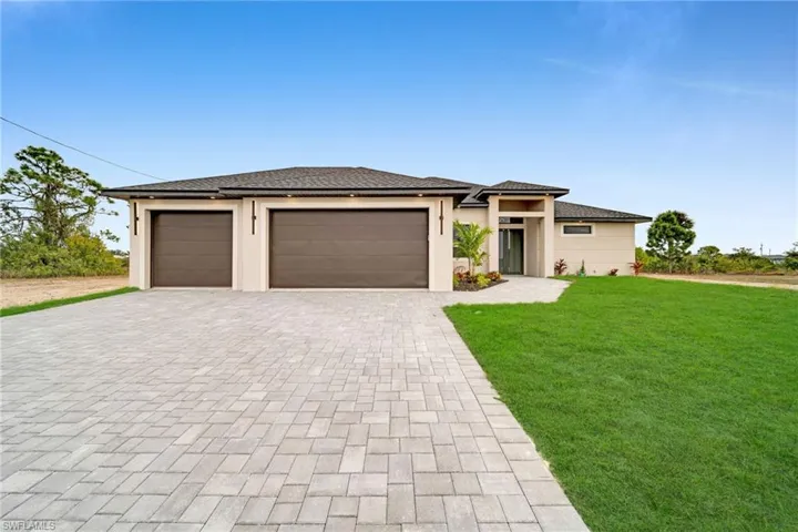 Prairie-style home with a front lawn, decorative driveway, an attached garage, and stucco siding
