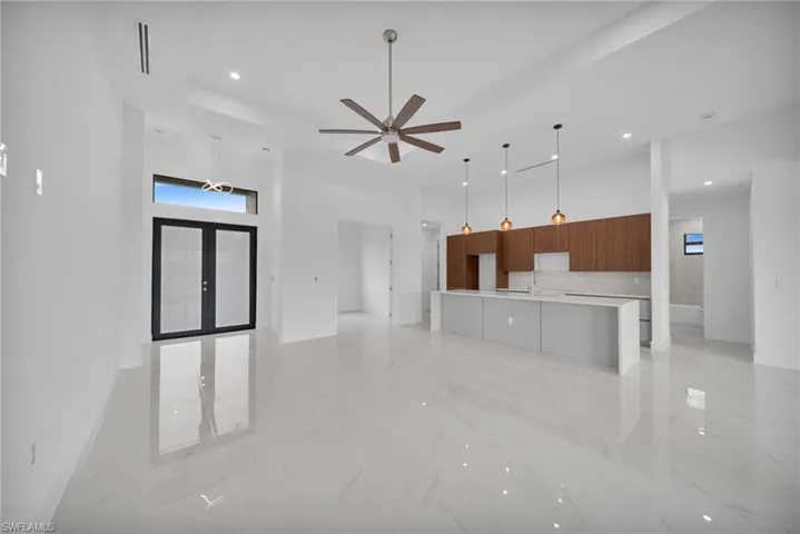 Unfurnished living room with a towering ceiling, recessed lighting, light marble finish floors, ceiling fan, and french doors