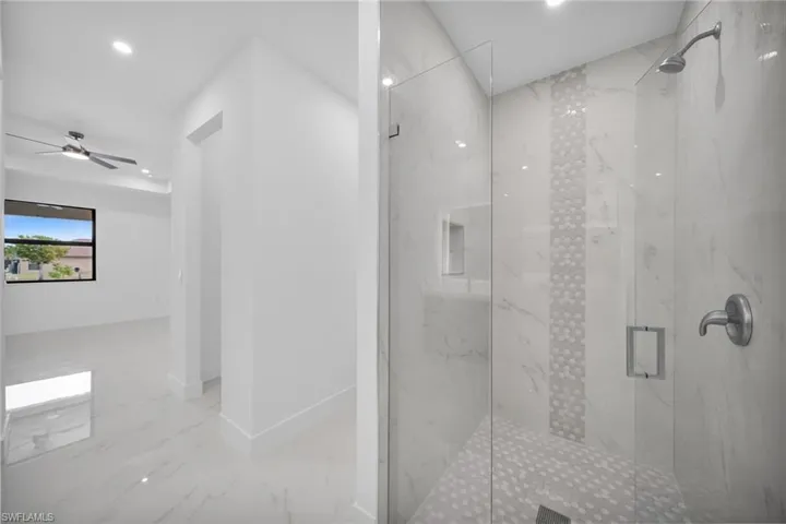 Bathroom featuring a marble finish shower, light marble finish floors, and recessed lighting