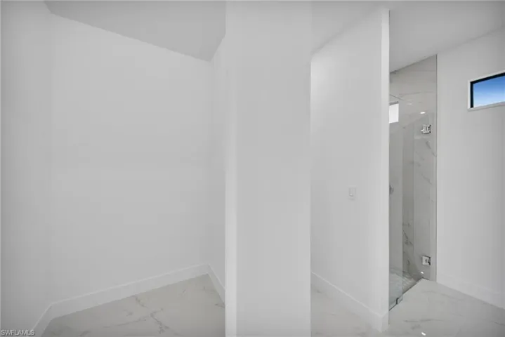 Bathroom featuring light marble finish flooring and a marble finish shower