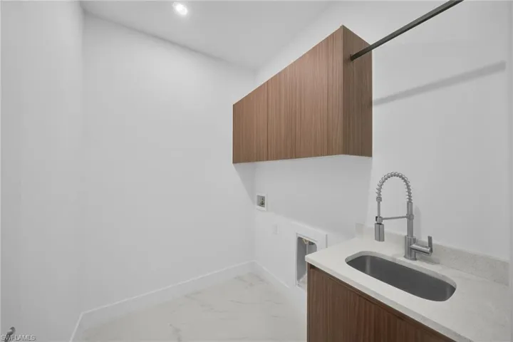 Laundry room featuring light marble finish flooring, washer hookup, and cabinet space