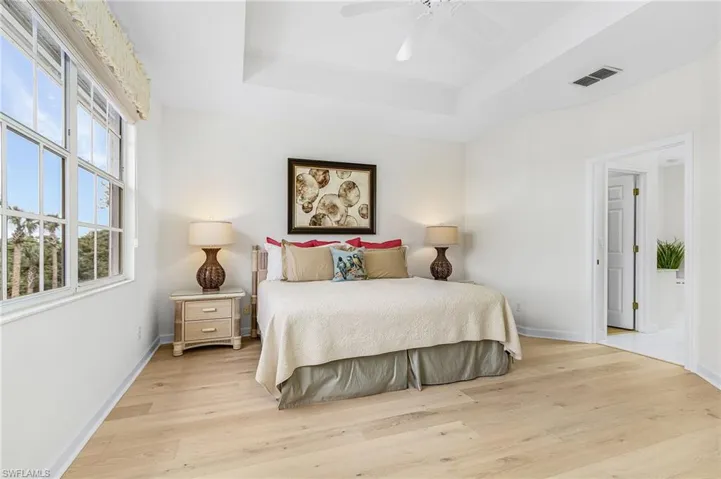 Bedroom featuring a raised ceiling, light wood flooring, with views of the golf course