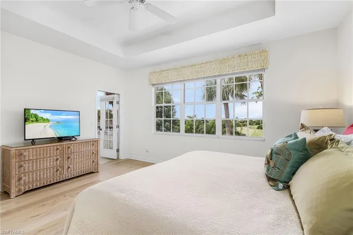 Bedroom featuring a raised ceiling, light wood flooring, with views of the golf course