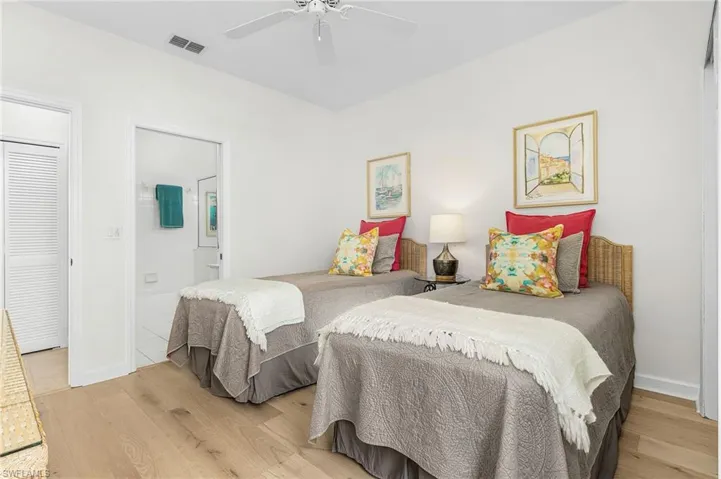 Bedroom #2 with light wood flooring, closet, large windows and ensuite bathroom