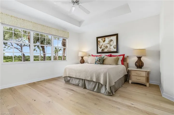 Bedroom featuring a raised ceiling, light wood flooring, with views of the golf course