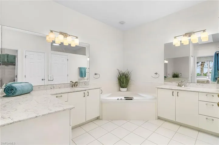 Full bathroom featuring two vanities, light tile floors, ensuite bathroom, separate shower and  bathtub