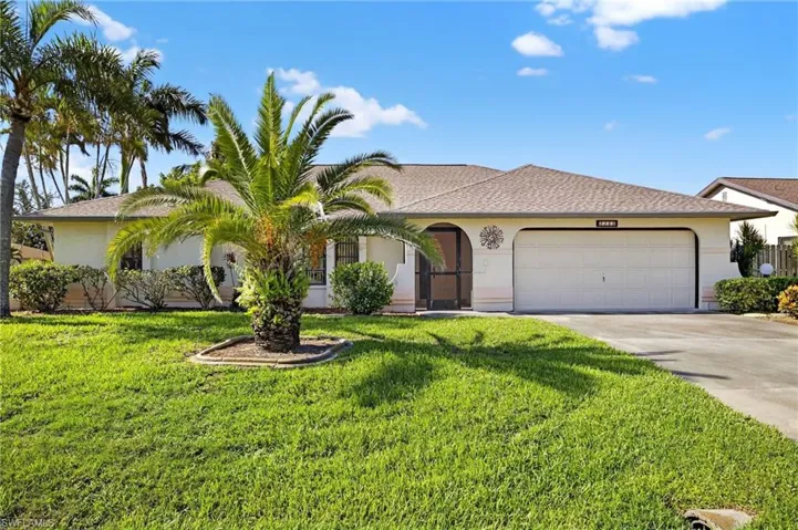 View of front of property featuring an attached garage, driveway, stucco siding, and a front lawn