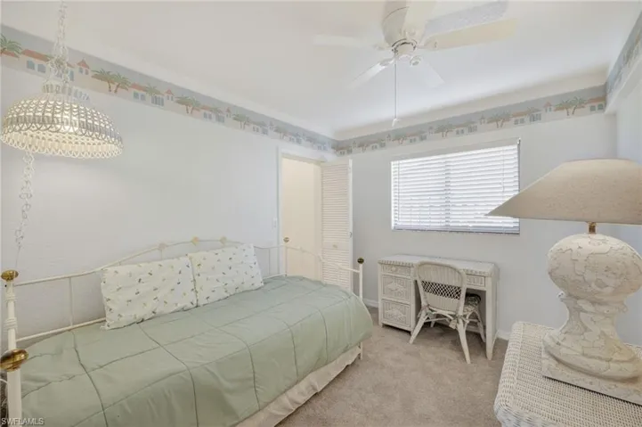 Carpeted bedroom with a ceiling fan and baseboards