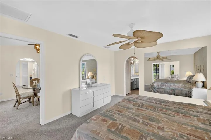 Bedroom featuring arched walkways, multiple windows, carpet, and ceiling fan