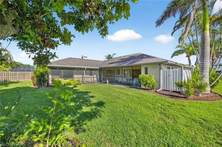 Back of property with a sunroom, stucco siding, and roof with shingles