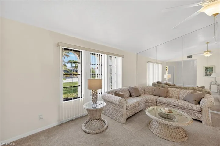 Living room with a ceiling fan, carpet flooring, and vaulted ceiling