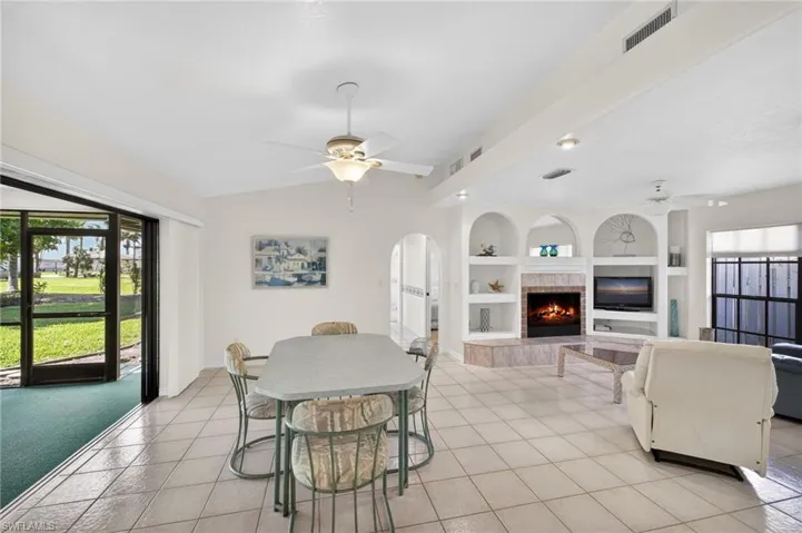 Dining space featuring a ceiling fan, light tile patterned flooring, a fireplace, and built in features