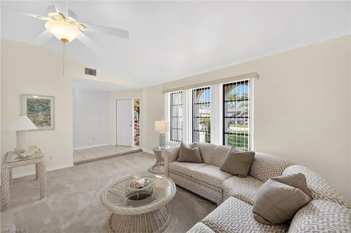 Carpeted living room with vaulted ceiling and a ceiling fan