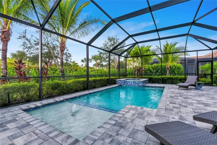 View of swimming pool with an in ground hot tub, a patio, pool water feature, and a lanai