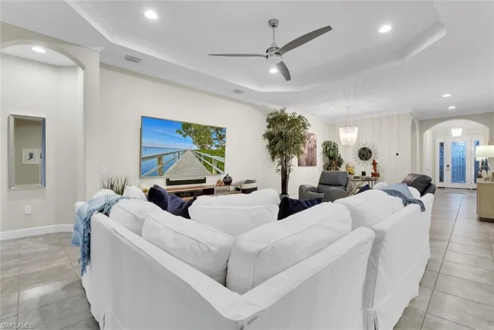 Tiled living room featuring ornamental molding, ceiling fan, and a raised ceiling