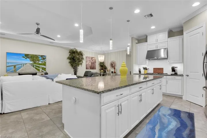 Kitchen featuring dark stone countertops, a center island, white cabinets, and ceiling fan