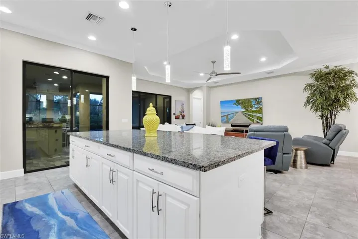 Kitchen with ceiling fan, hanging light fixtures, white cabinets, a center island, and light tile patterned floors