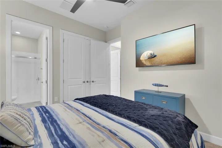 Carpeted bedroom with connected bathroom, a closet, and ceiling fan