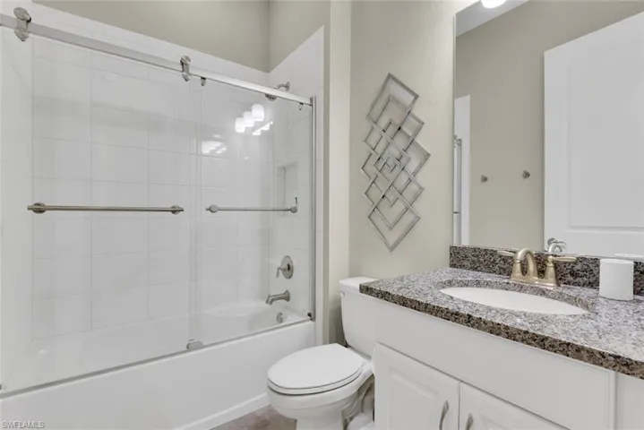 Full bathroom featuring bath / shower combo with glass door, toilet, and vanity
