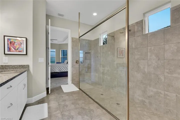 Bathroom featuring tile patterned flooring, a tile shower, crown molding, vanity, and ceiling fan
