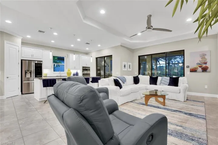 Living room featuring sink, ceiling fan, light tile patterned floors, a tray ceiling, and ornamental molding