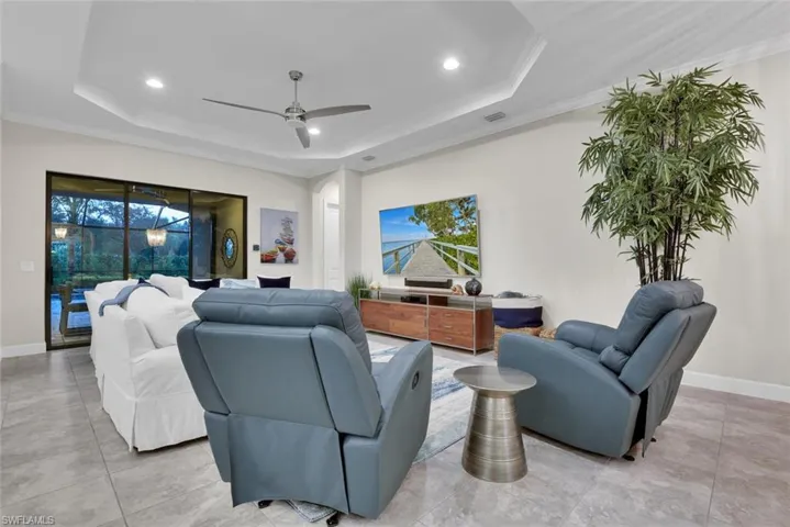 Tiled living room with a tray ceiling, ceiling fan, and a healthy amount of sunlight