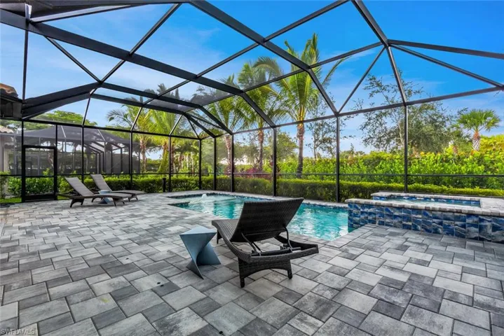 View of swimming pool featuring an in ground hot tub, pool water feature, a patio area, and a lanai