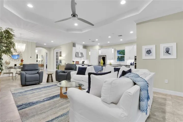 Tiled living room with ceiling fan, crown molding, and a tray ceiling