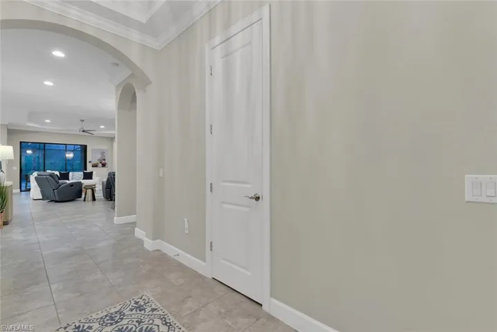 Hallway featuring light tile patterned floors and crown molding